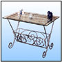 Magazine Table   A simple utility table with beveled glass top in combination with a magazine holder. Hot forged iron with antiqued finish.   Sizes: H : 24"  W : 98"  L : 30"  WT :     Frame in 1/2" Circular Tubing.  End Scrolls in Matching 1/2" forged round stock.    Aesthetics Filling with 3/8" forged Sq. Solid Stock.       